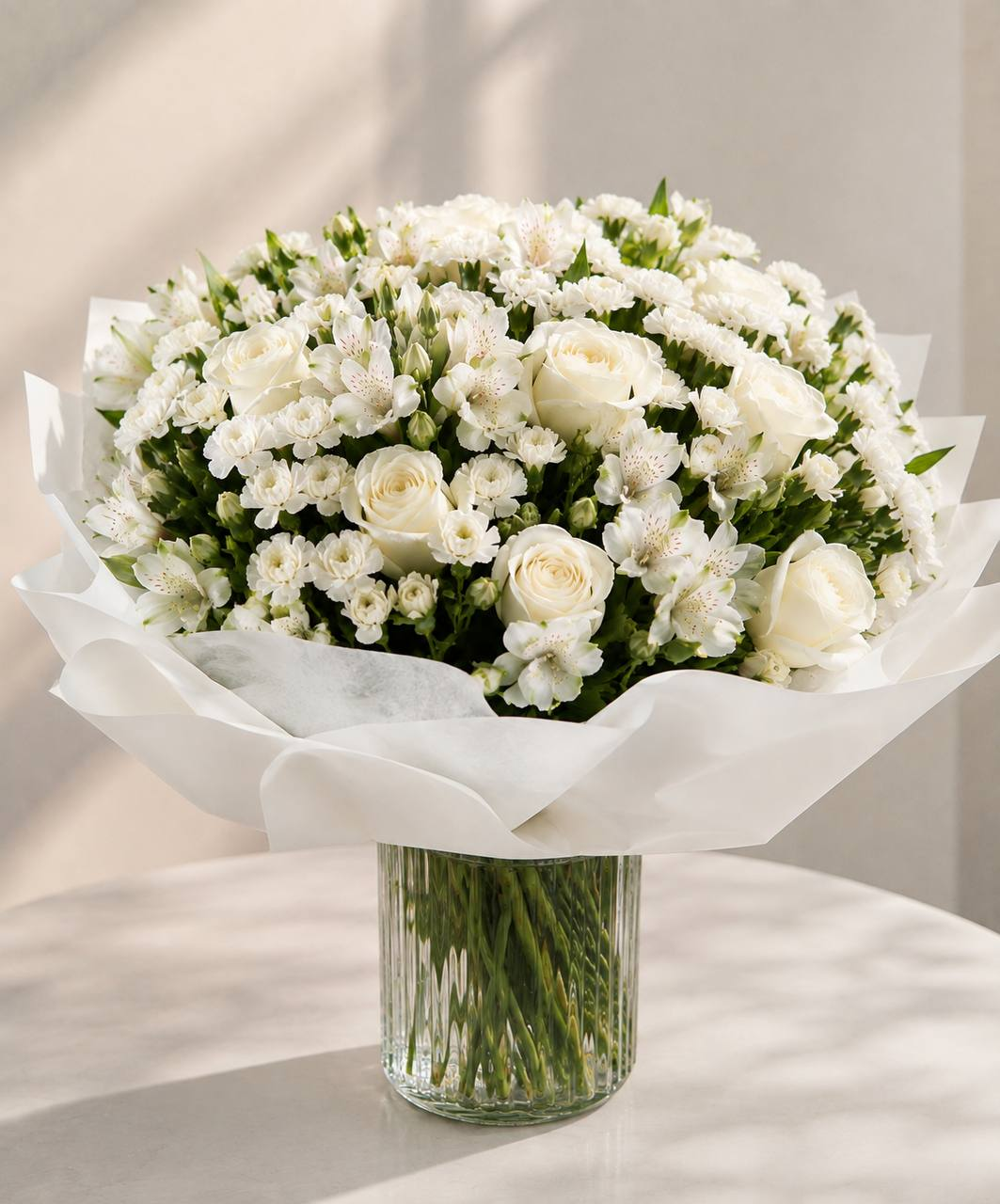 Wrapped white Glen and Bloom bouquet presented with a glass vase